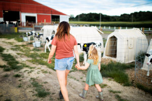 Wisconsin dairy farmer and her daughter walking on farm by calf hutches