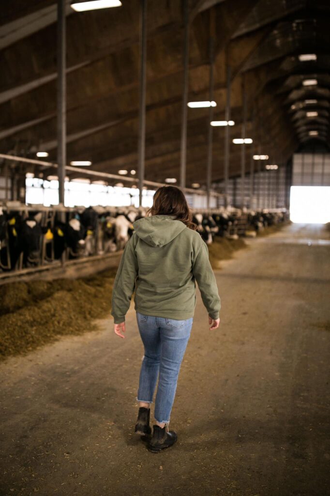 female walking through Wisconsin dairy farm forestall barn