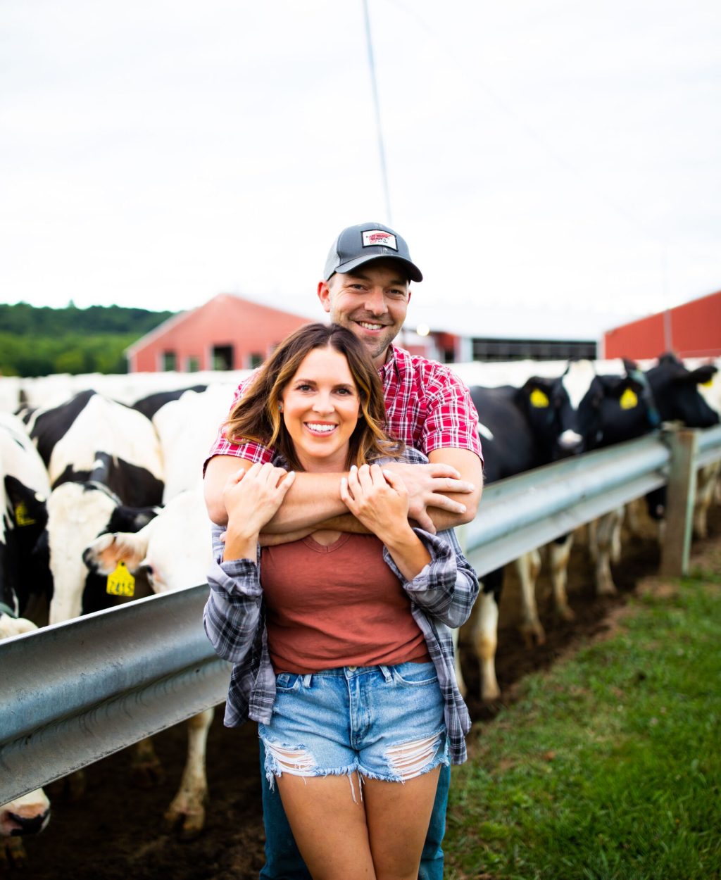 Wisconsin dairy farm couple in front of cows on the farm