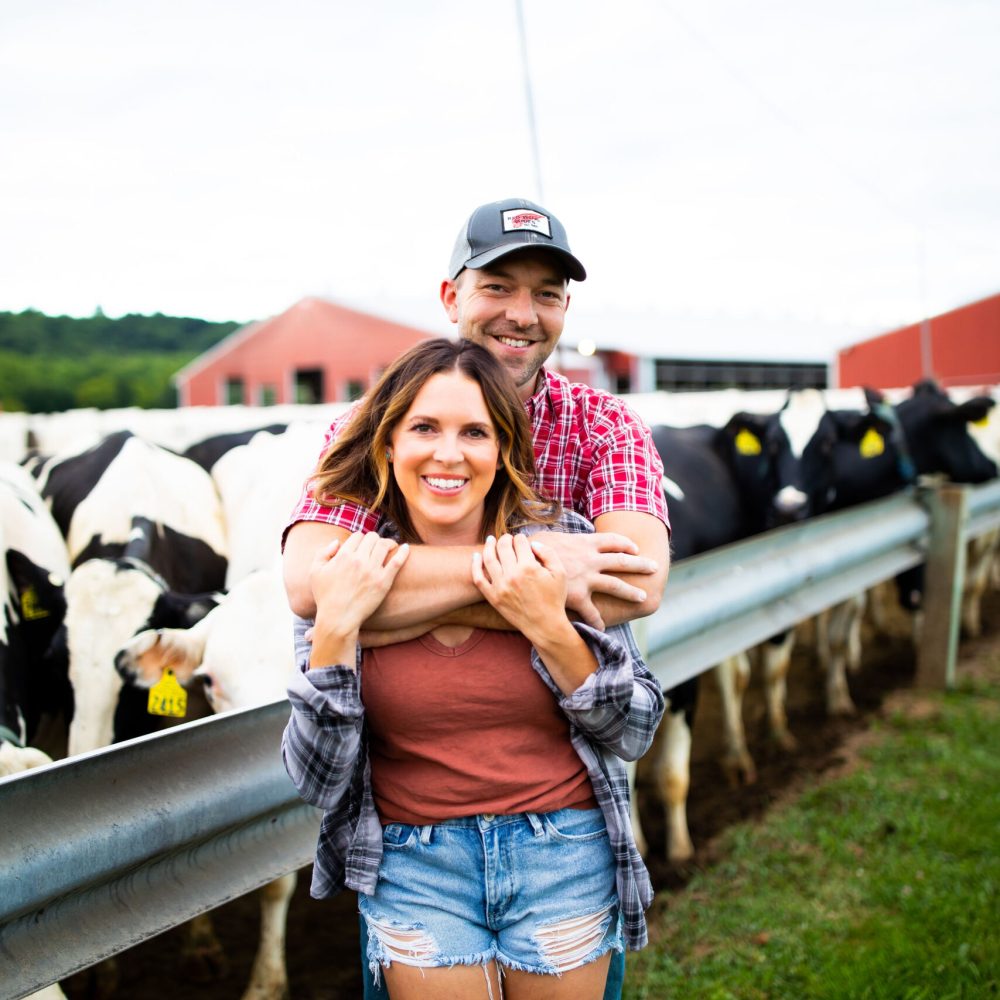 Wisconsin dairy farm couple in front of cows on the farm